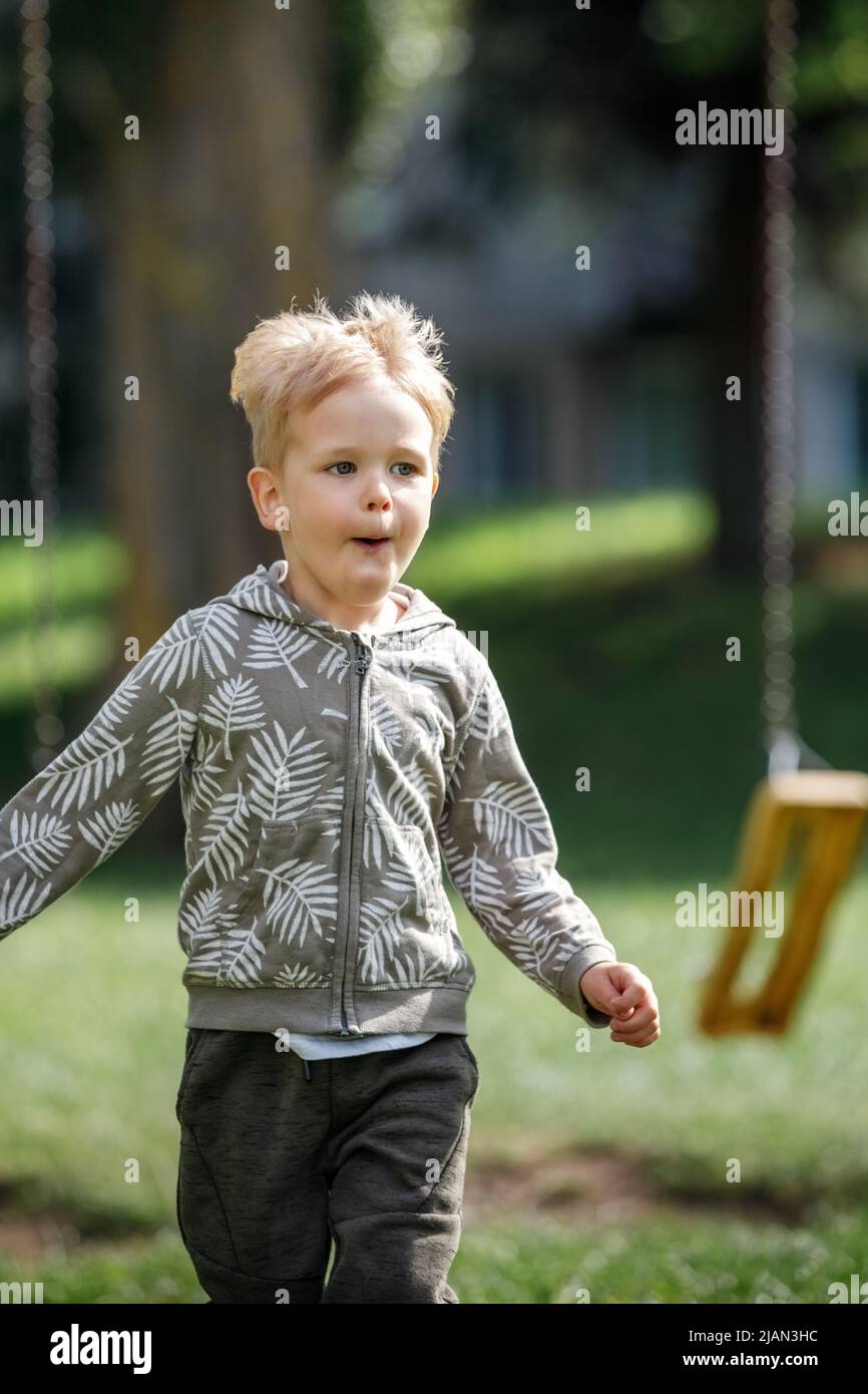 Adorable little boy running outside in slow-motion towards camera happy child runs. Stock Photo