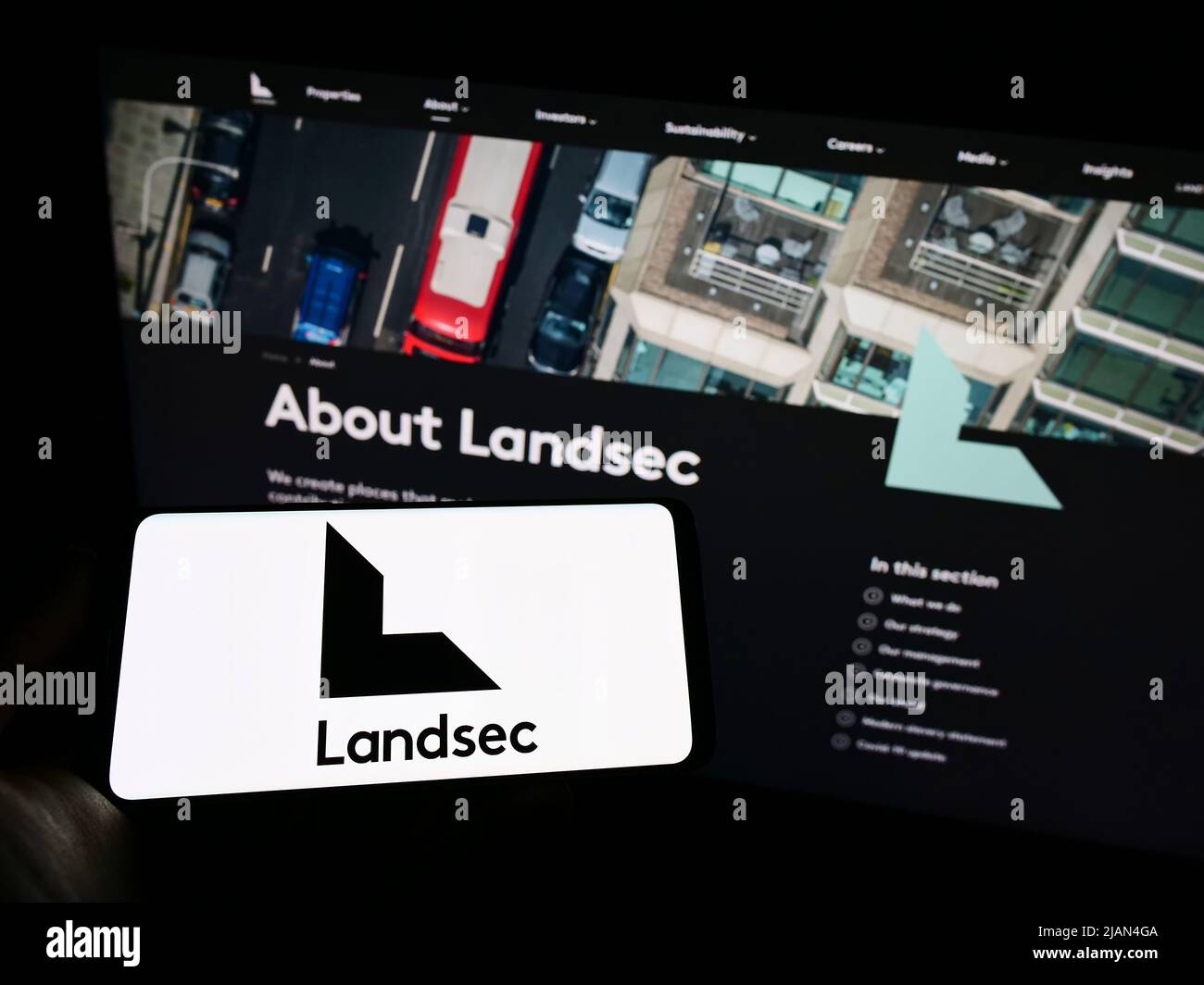 Person holding smartphone with logo of company Land Securities Group plc (Landsec) on screen in front of website. Focus on phone display. Stock Photo