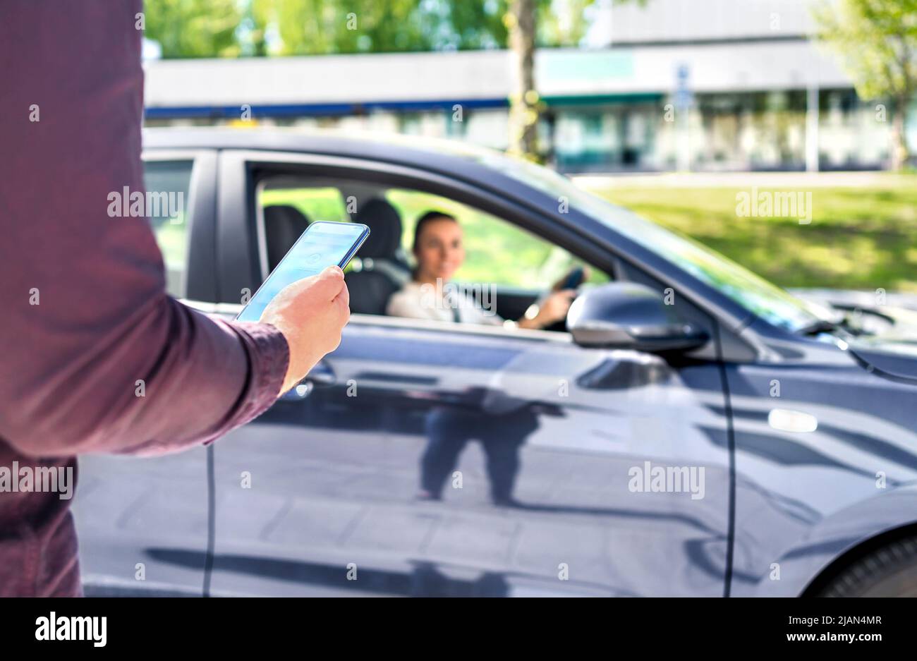 Taxi phone app for cab or car ride share service. Customer waiting driver to pick up on city street. Man holding smartphone. Mobile and online booking. Stock Photo