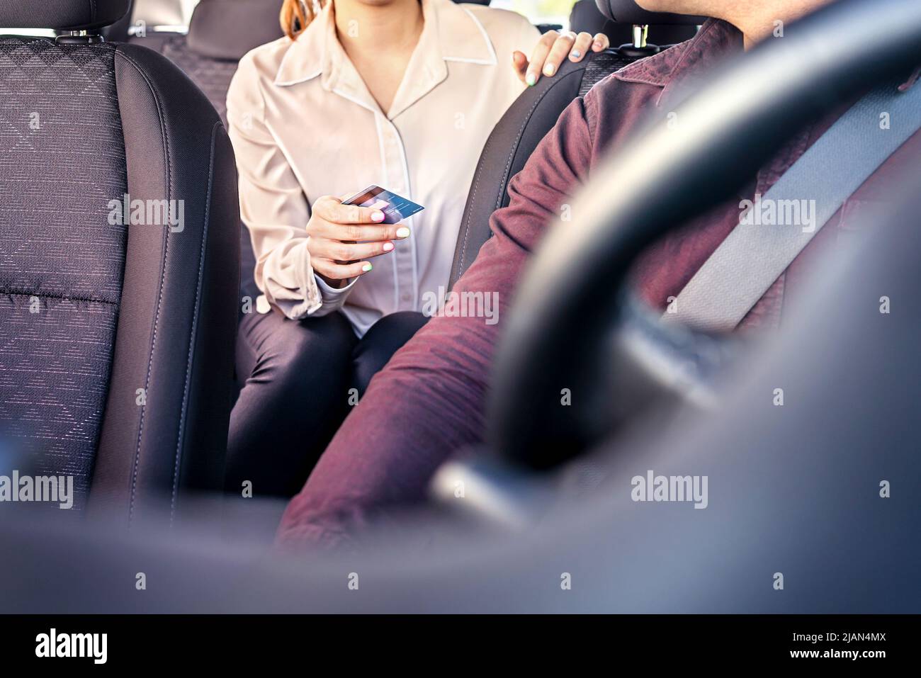 Taxi and card payment. Customer paying cab fare. Woman giving money to driver. Transaction security, scam or fraud concept. Passenger purchase ride. Stock Photo