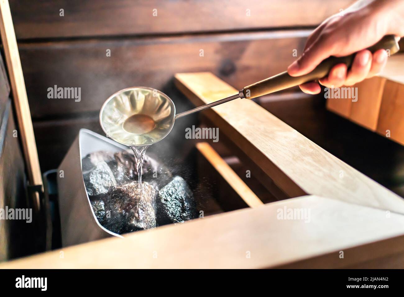 Sauna in Finnish spa. Hot steam, water on stones. Man in wellness and health room in Finland. Warm temperature bath therapy. Traditional summer cabin. Stock Photo