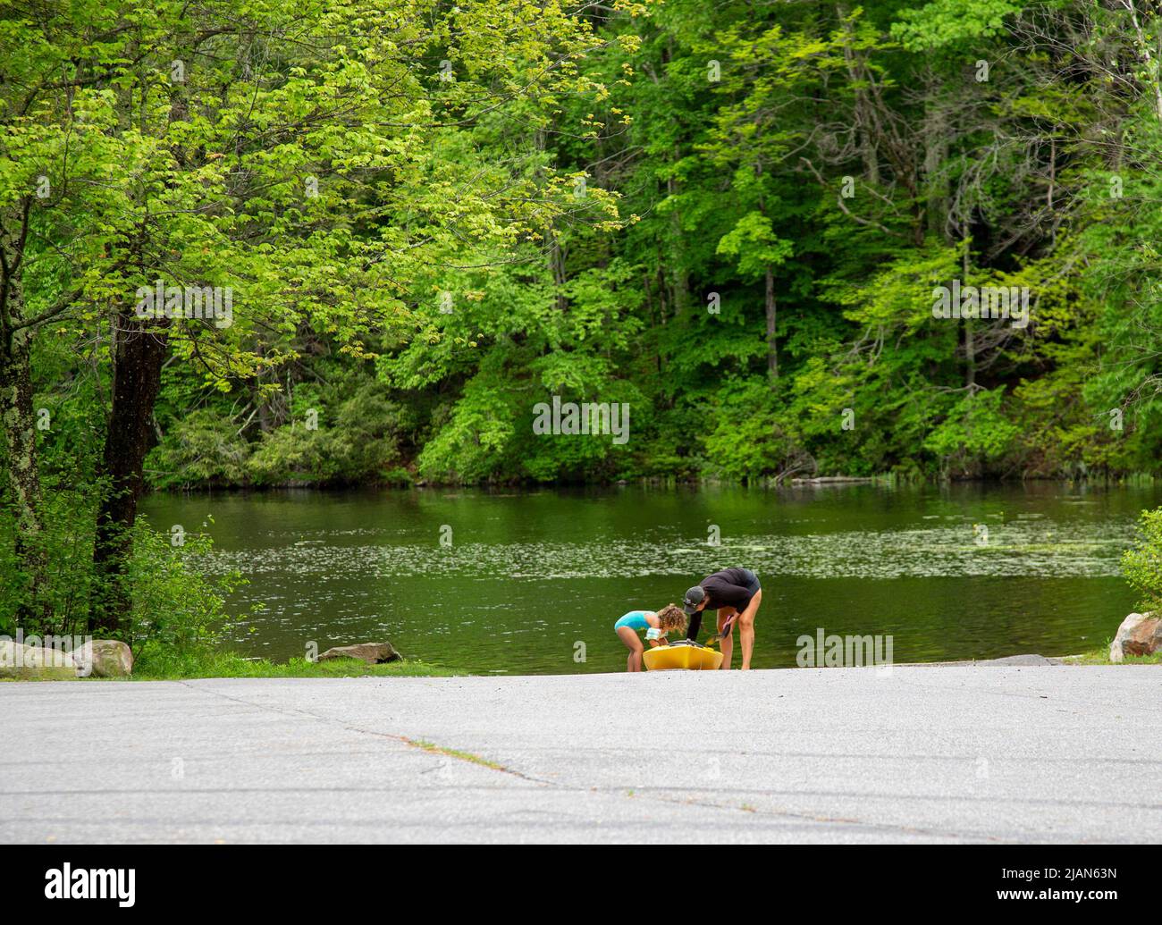 Mother and child putting a kayak into a lake Stock Photo