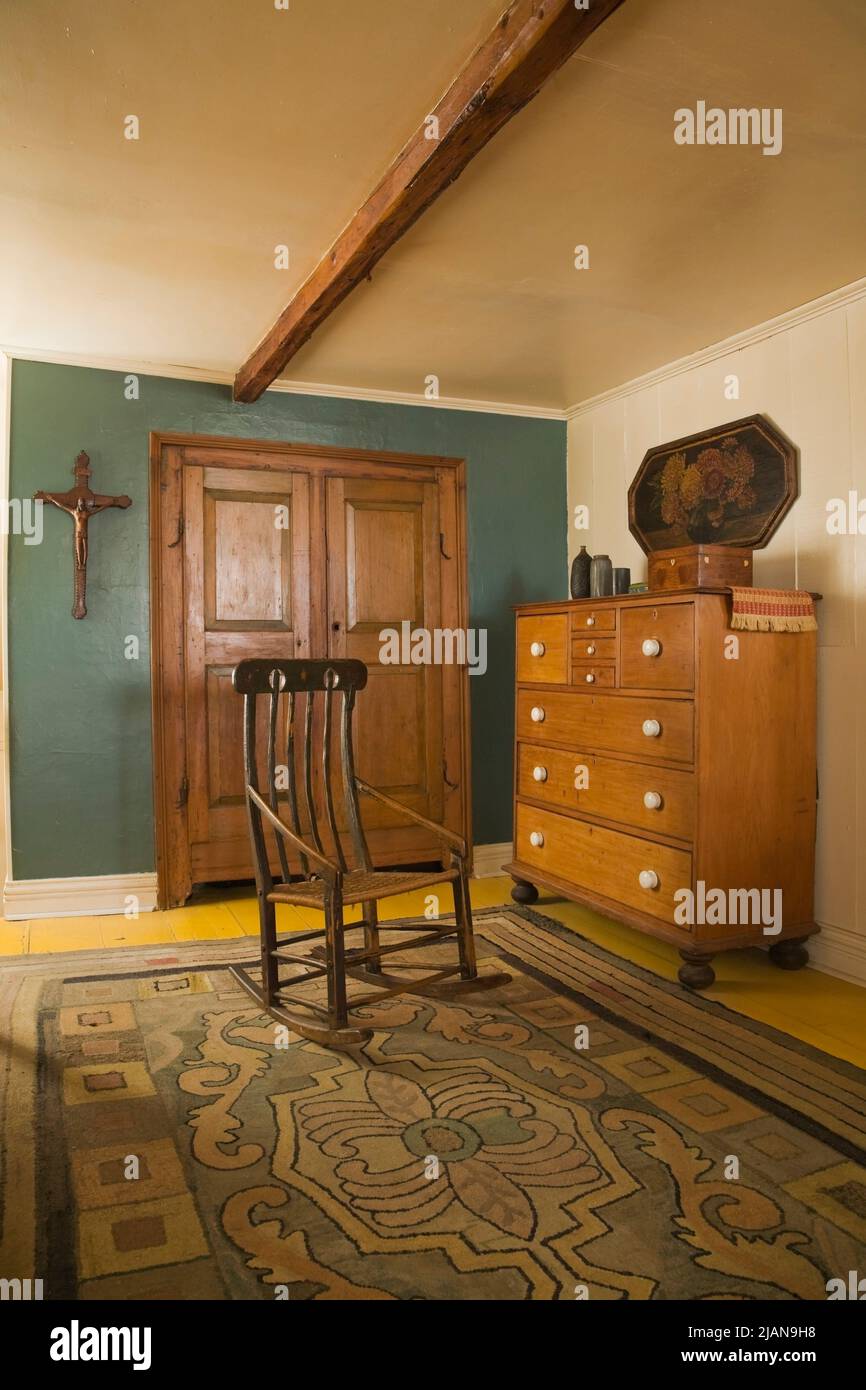 Antique rocking chair and chest of drawers in main bedroom on upstairs floor inside old circa 1810 Canadiana cottage style home. Stock Photo