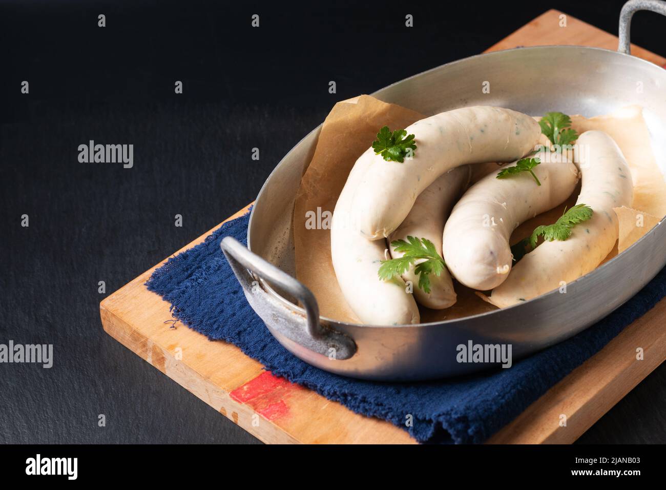 Food concept homemade organic German white sausage Weisswurst in aluminum tray on black slate stone with copy space Stock Photo