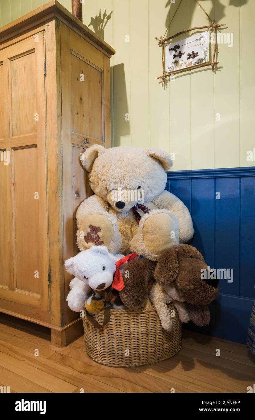Plush toys in wicker basket and armoire in bedroom on upstairs floor