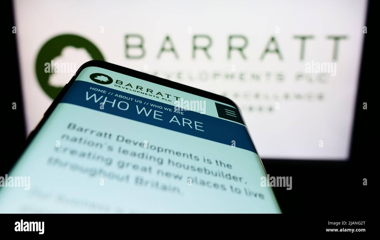 Smartphone with webpage of property company Barratt Developments plc on screen in front of business logo. Focus on top-left of phone display. Stock Photo