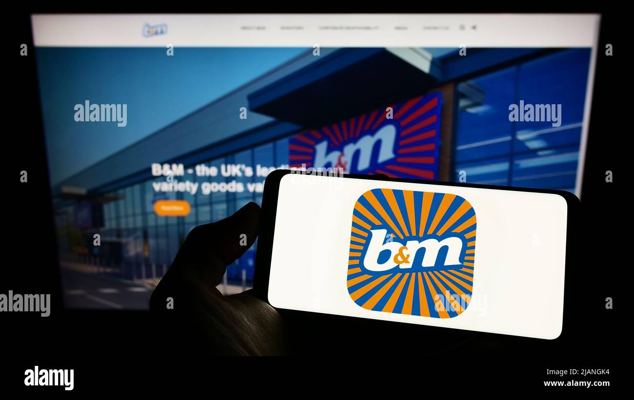 Person holding smartphone with logo of company BM European Value Retail S.A. on screen in front of website. Focus on phone display. Stock Photo