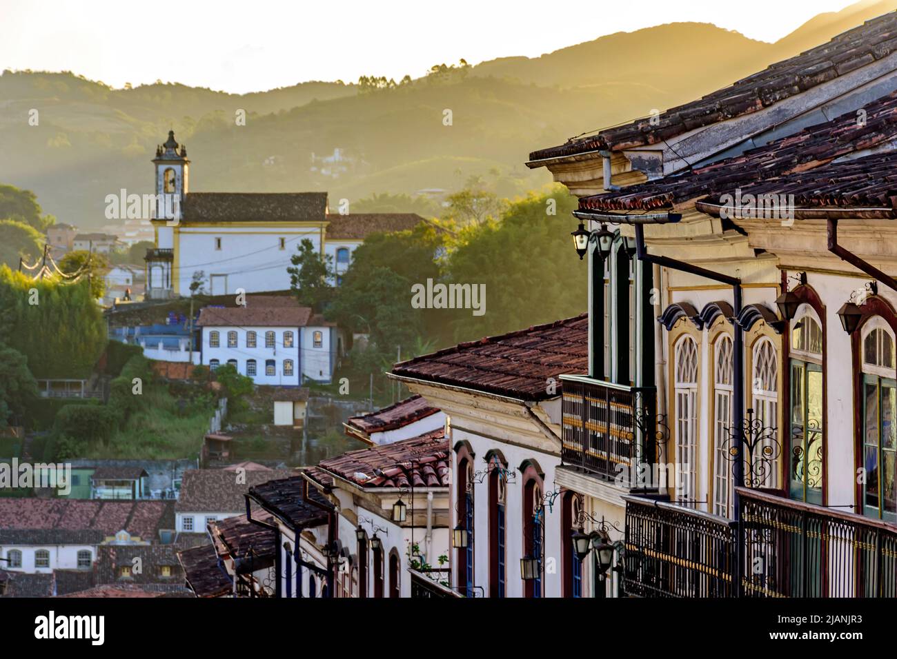 View of historic colonial style houses and church in the background on the hills of Ouro Preto city, Minas Gerais state, Brazil Stock Photo