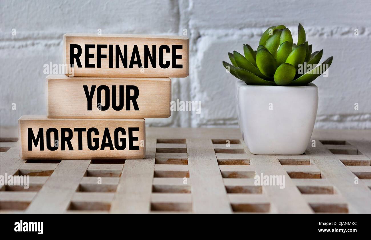 Business concept. Text REFINANCING YOUR MORTGAGE on wooden blocks and beautiful background with cactus Stock Photo