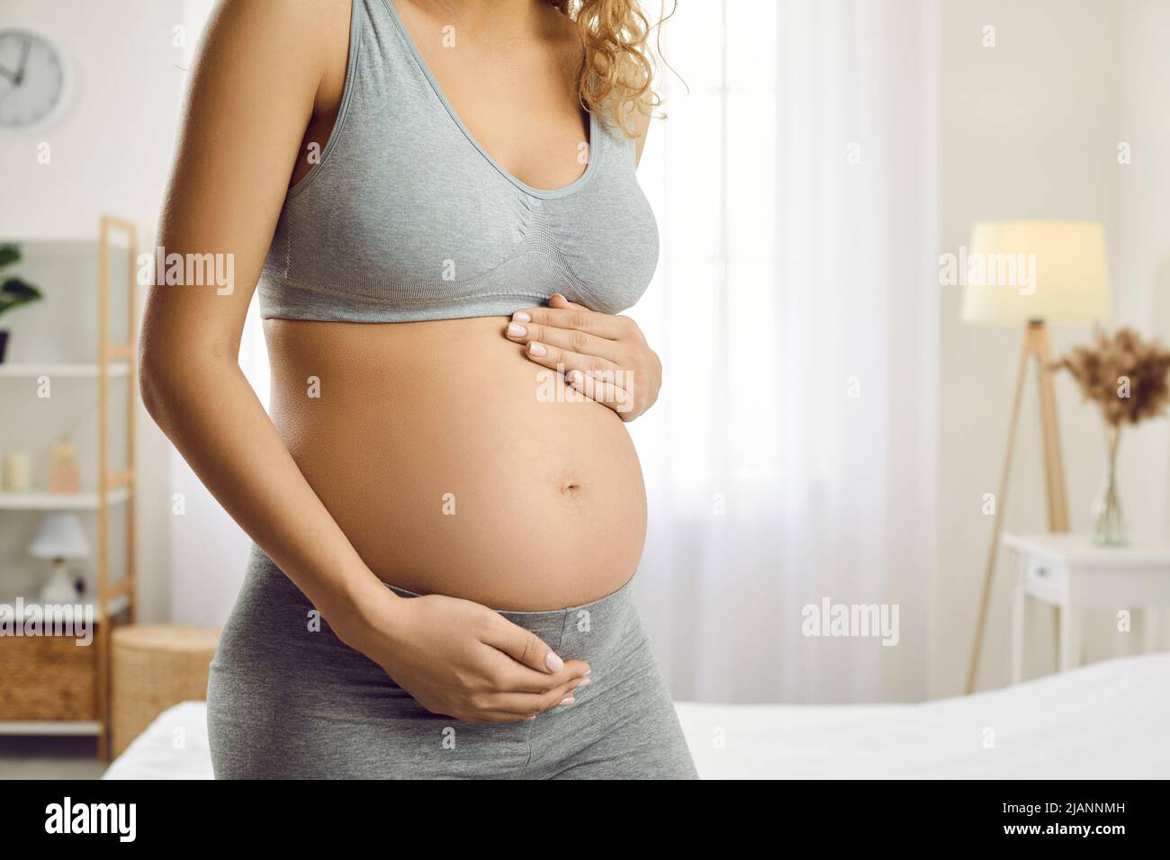 Young woman expecting baby hugs her tummy enjoying tender moments of motherhood. Stock Photo