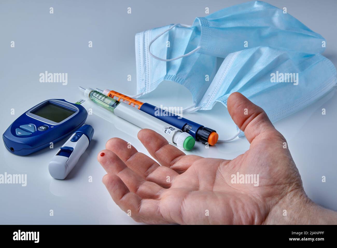 Male hand with a drop of blood on a finger, insulin syringe pens