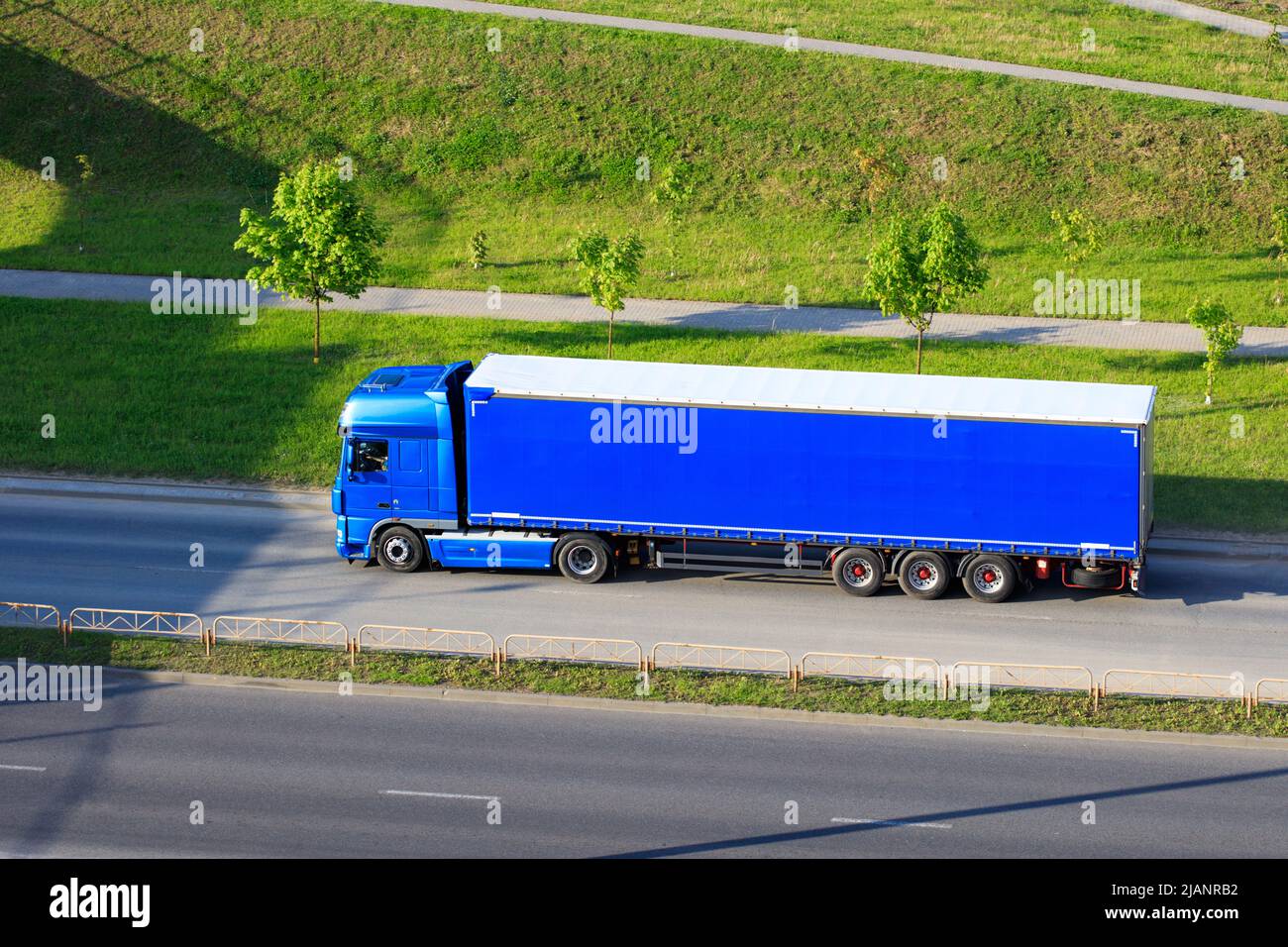 Blue semi truck lorry with trailer in motion on freeway. Big commercial cargo van, freight car