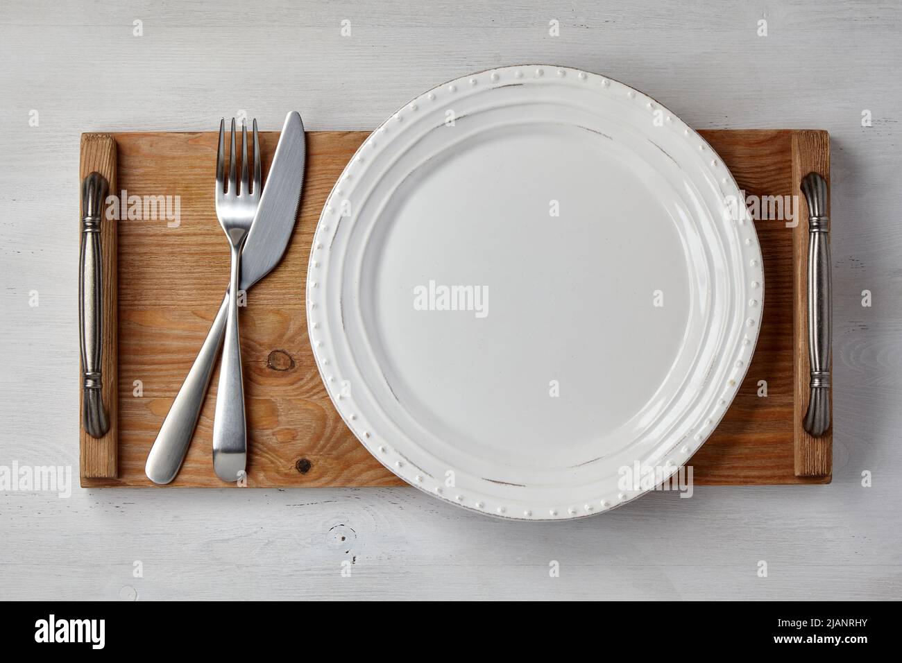 White handmade plate and cutlery on a dark wooden tray. Menu