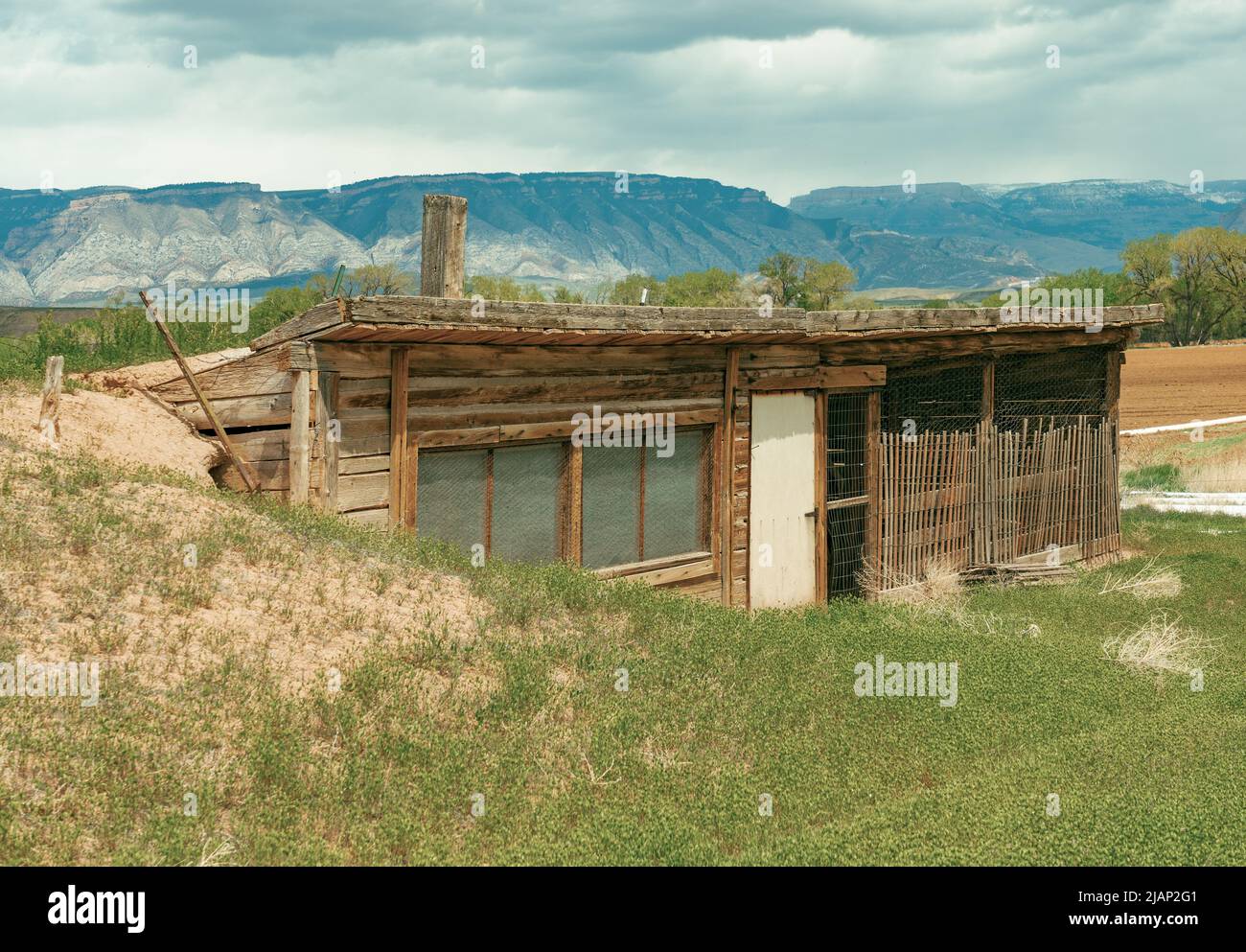 Old wood chicken coop with windows is built out from underground. Earth