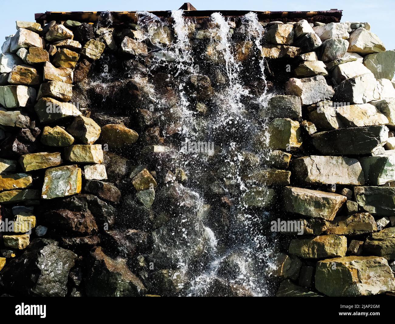Stone Splashing A splashing waterfall flows down wall made of large sharp stones ...