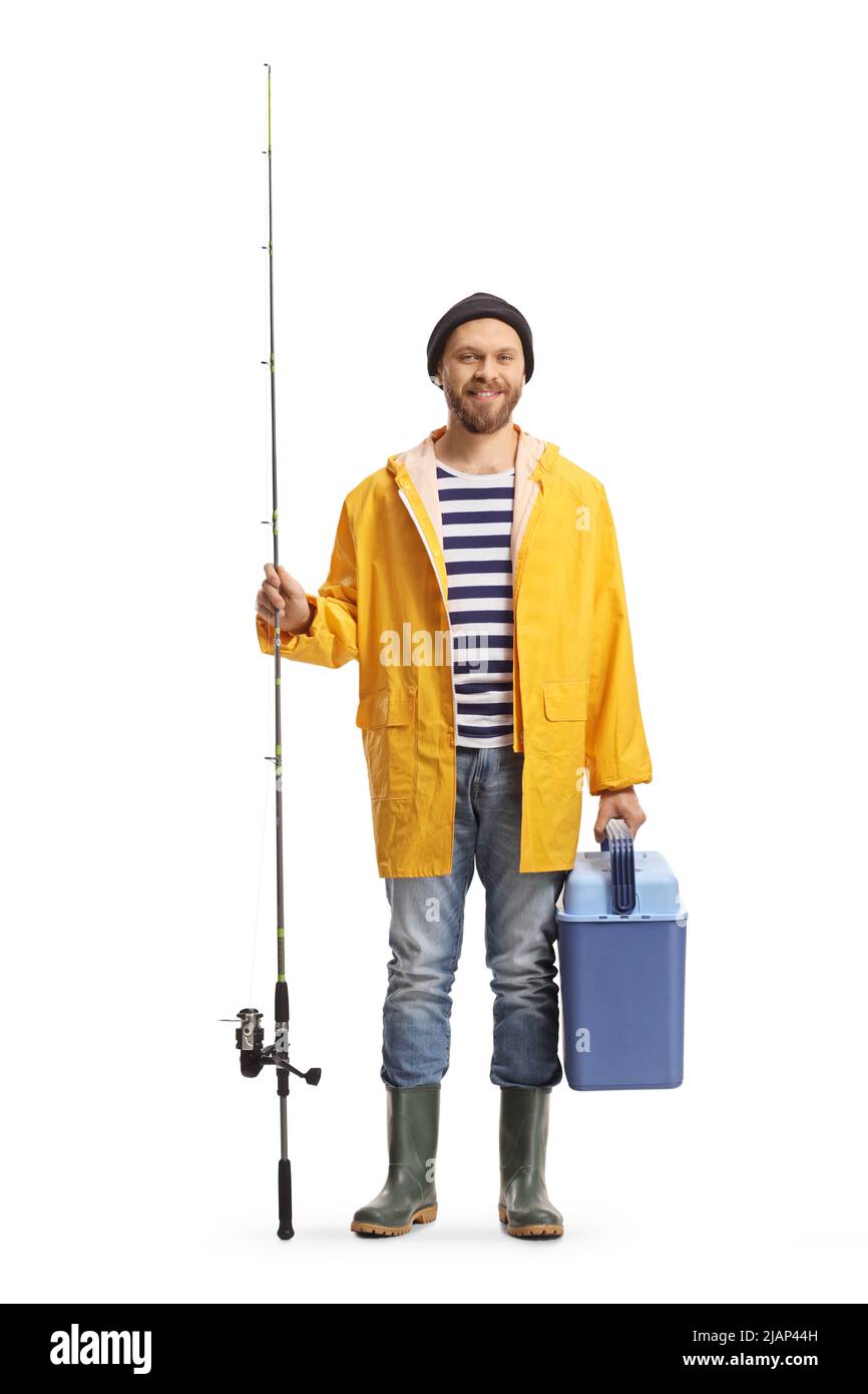 Young man in a raincoat and boots holding a fishing rod and a fridge isolated on white background Stock Photo