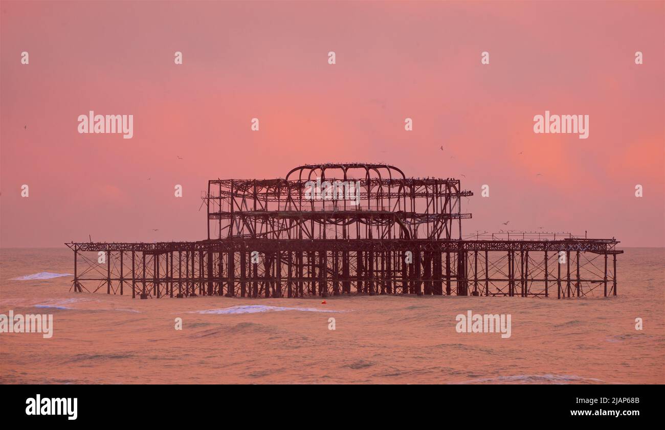 Rusting remains of the decrepit West Pier against a dusky pink sky. Brighton & Hove, Sussex, England, UK. Stock Photo
