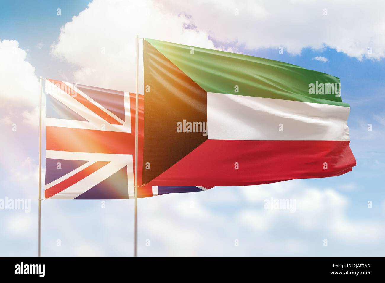 Sunny blue sky and flags of kuwait and united kingdom Stock Photo