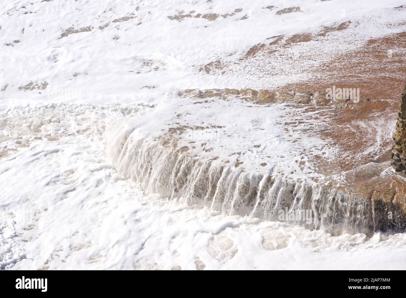 Water spilling off the base of a sea defence groyne on Brighton beach, East Sussex, England, UK Stock Photo