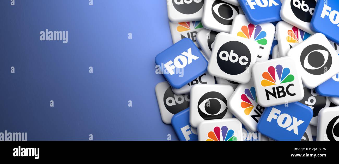 Logos of the major US broadcast television networks NBC, CBS, ABC and FOX on a heap on a table. Copy space. Web banner format. Stock Photo