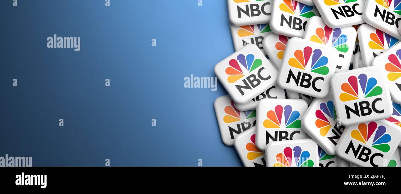 Logos of the US broadcast television network NBC National Boradcasting Company on a heap on a table. Copy space. Web banner format. Stock Photo