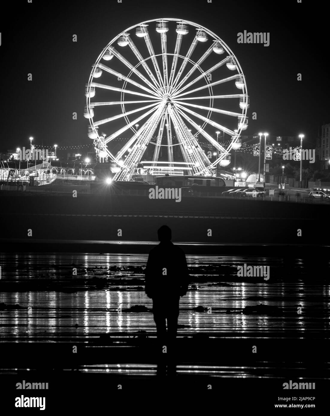 A nocturnal view across the sand of Seaburn beach towards an illuminated Ferris wheel Stock Photo
