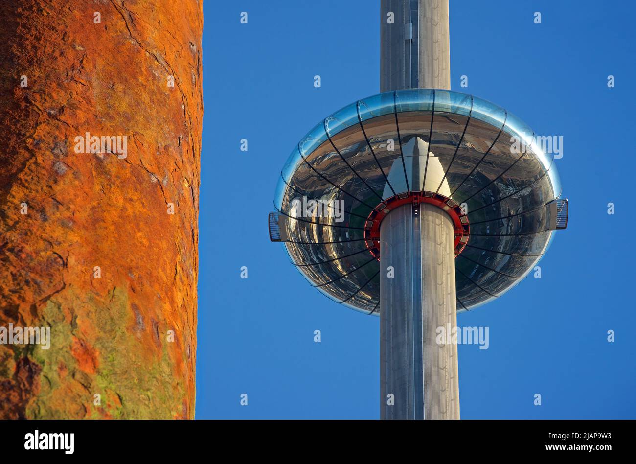 The i360 pod rising up its supporting tower, Brighton. Structural pylon from the now derelict West Pier to one side. Brighton & Hove, England, East Sussex, England. Old and new juxtaposition. Stock Photo