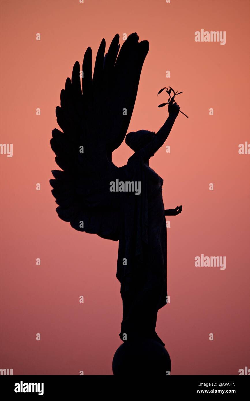 Silhouette of the Peace Statue of an Angel on the Brighton Hove boundary. Monument erected 1912. Brighton and Hove, England. Rich dusky pink sky at dusk. Stock Photo