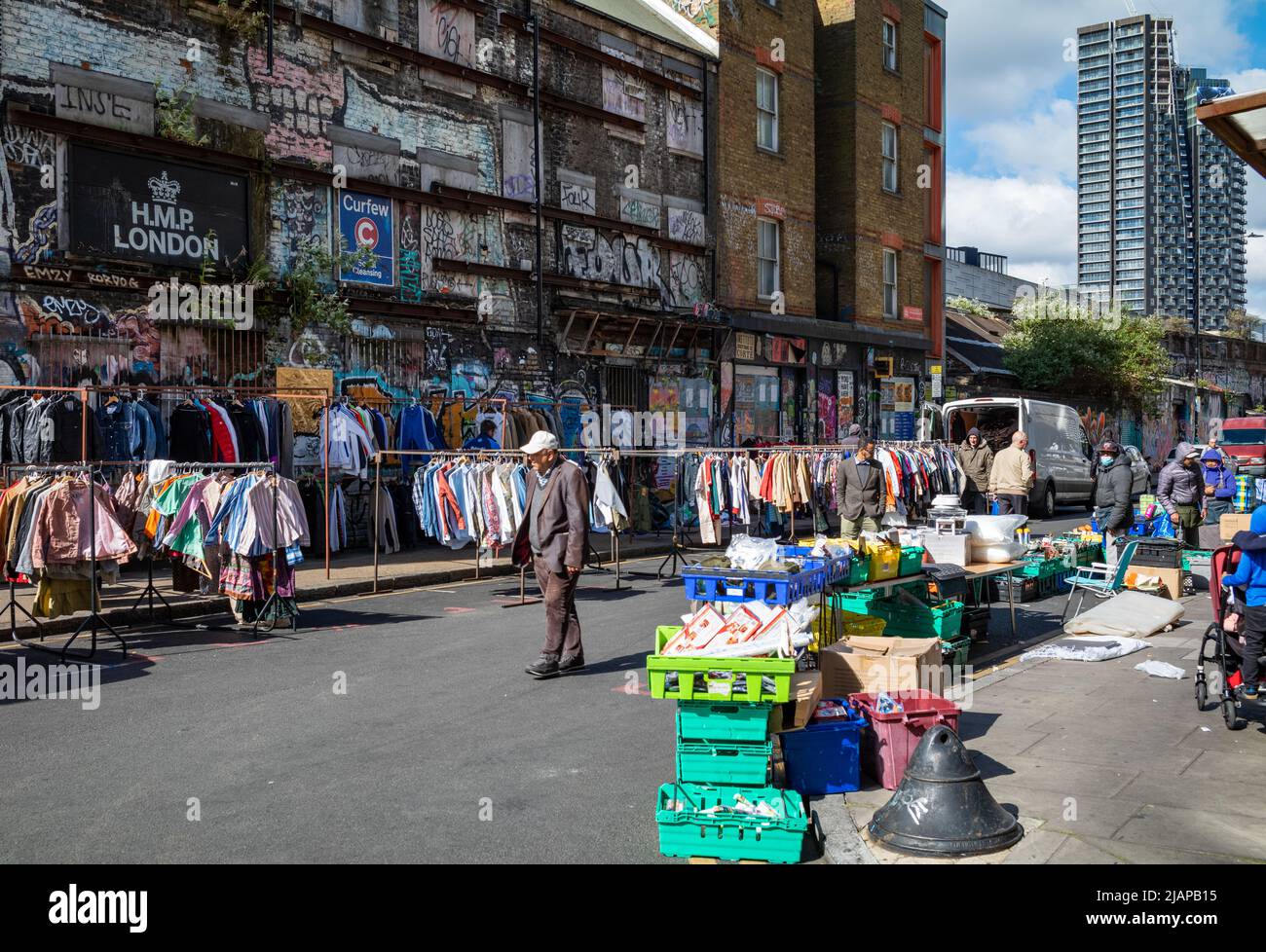 An elderly man walks past a second hand clothes stall at Brick Lane Market in East London, UK Stock Photo