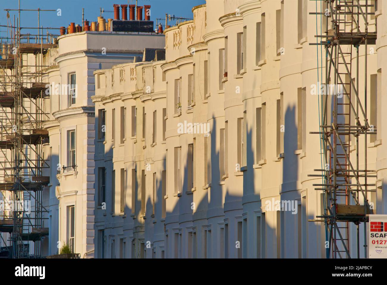 Compressed perspective of regency architecture of Lansdown Place, Hove, Brighton and Hove, East Sussex, England UK. Scaffoldfing and stucco-fronted facades in a residential street. Stock Photo