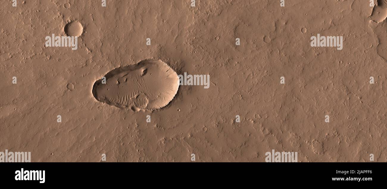 A Martian shield volcano with a summit caldera.Although there are a few giant shield volcanoes on Mars, there are also many smaller ones. NASA is interested in imaging the vent regions of volcanoes to understand volcanic processes, and search for signs of recent activity. This HiRISE image shows that the summit caldera is mantled by dust and covered by small impact craters, so this volcano hasnÕt been active recently enough to affect current atmospheric trace gases. This image is less than 5km (3mi) across.  An optimised and enhanced version of NASA imagery. Credit: NASA/JPL/UArizona Stock Photo