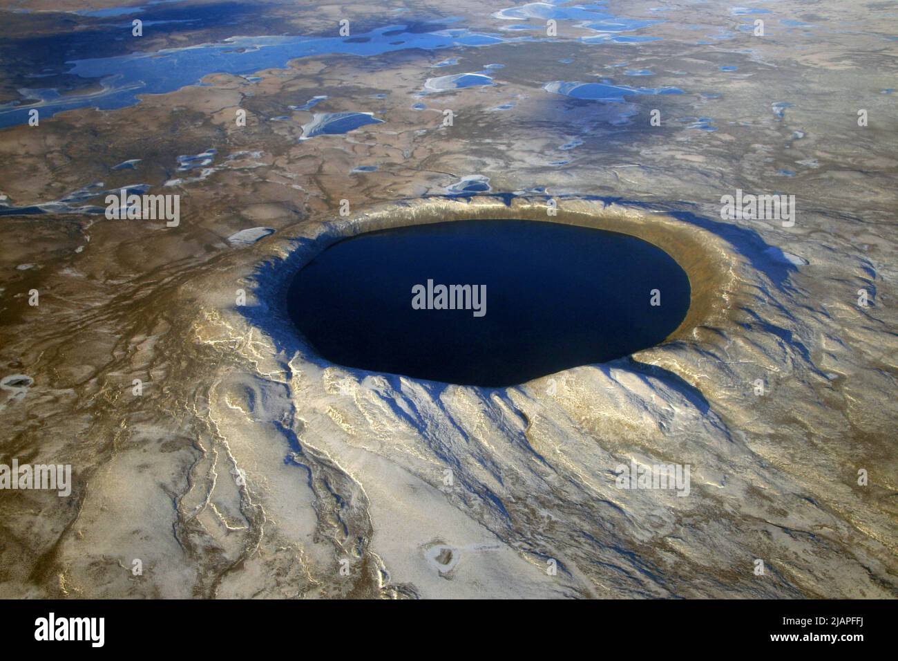 Pingualuit crater in Quebec, Canada, was formed millions of years ago by a meteorite striking the land, and today it is a deep lake. Pingualuit is 3.44 kilometers (2.14 miles) across and 267 meters (876 feet) deep. Also referred to as the Chubb Crater; New Quebec Crater. The crater and the surrounding area are now part of Pingualuit National Park. The only species of fish in the crater lake is the Arctic char.  An optimised and enhanced version of NASA imagery. Credit: NASA/D.Sarrazin Stock Photo