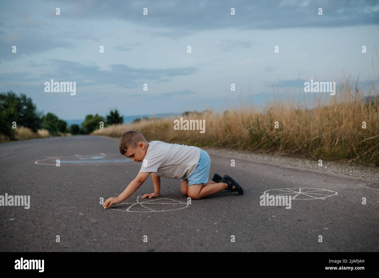 Little kid boy drawing with chalk on asphalt in summer Stock Photo - Alamy