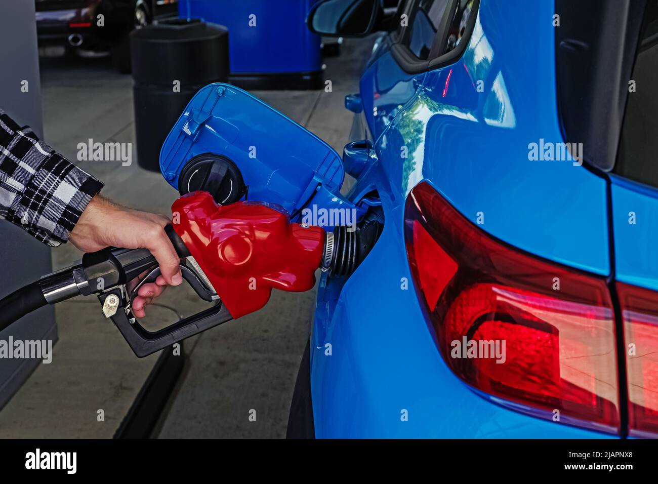Male hand holding pump filling gasoline into the car, close-up shot. Car refuel, gas price concept Stock Photo