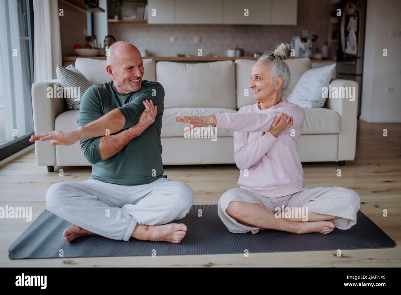Senior couple doing relaxation exercise together at home. Stock Photo
