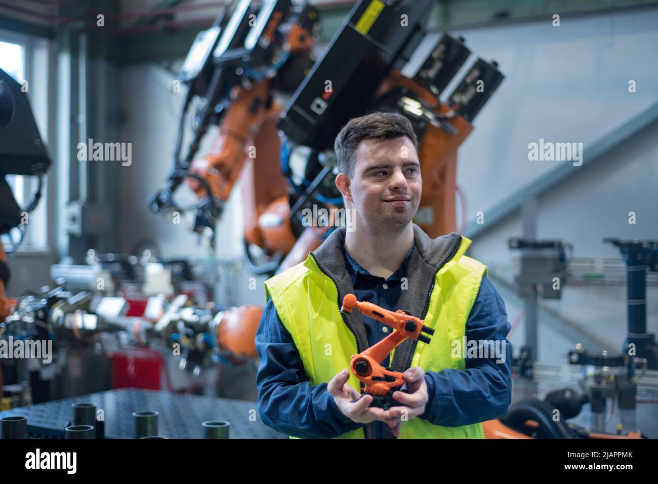 Young man with Down syndrome looking at blueprints when working in industrial factory, social integration concept. Stock Photo