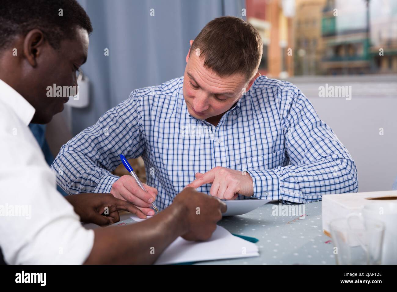 Serious man wit friend discussing documents at home Stock Photo