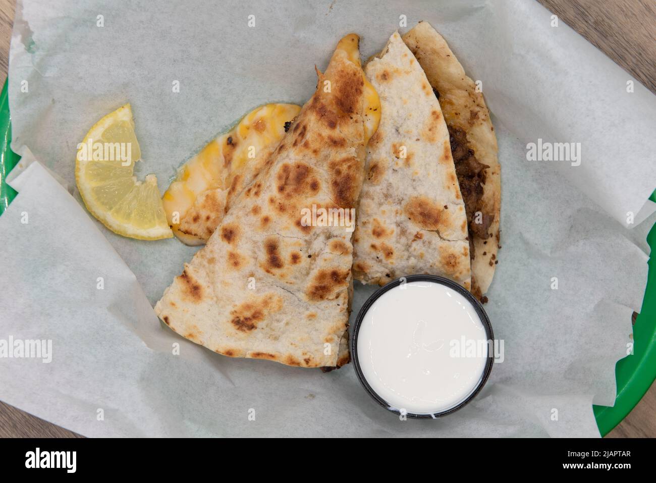 Overhead view of tempting crispy fried asada quesadilla loaded with grilled steak meat and cut into triangle pieces to eat. Stock Photo