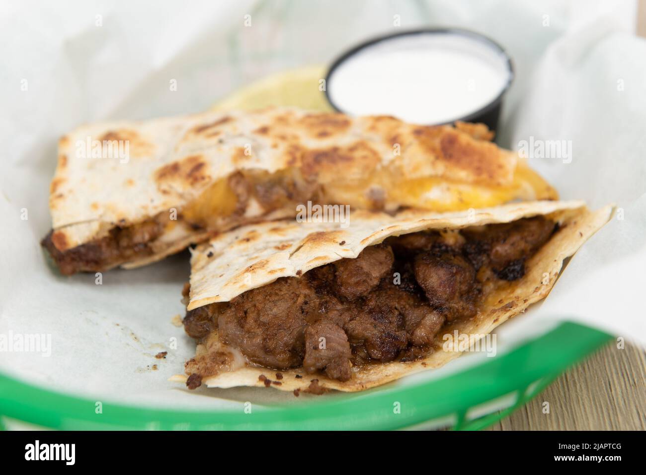Tempting crispy fried asada quesadilla loaded with grilled steak meat and cut into triangle pieces to eat. Stock Photo