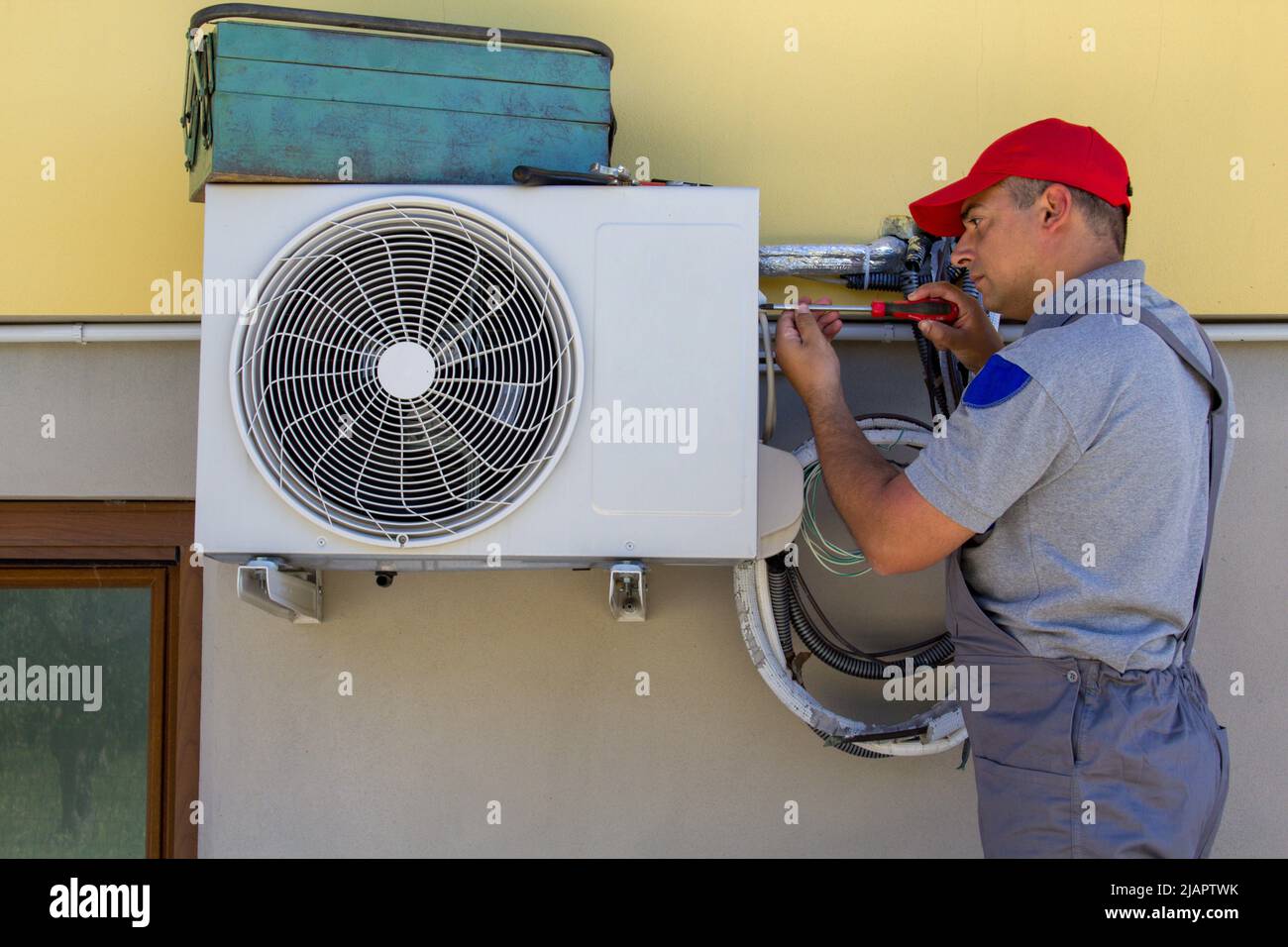 Image of a plumber with tools installing an air conditioner in a house