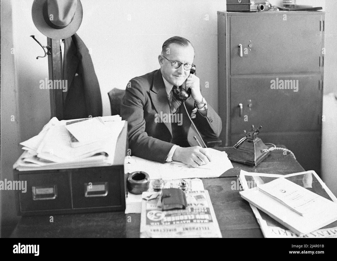 Man using telephone in the Fox Movietone offices (possibly in Sydney Australia) ca.  January 1938 Stock Photo