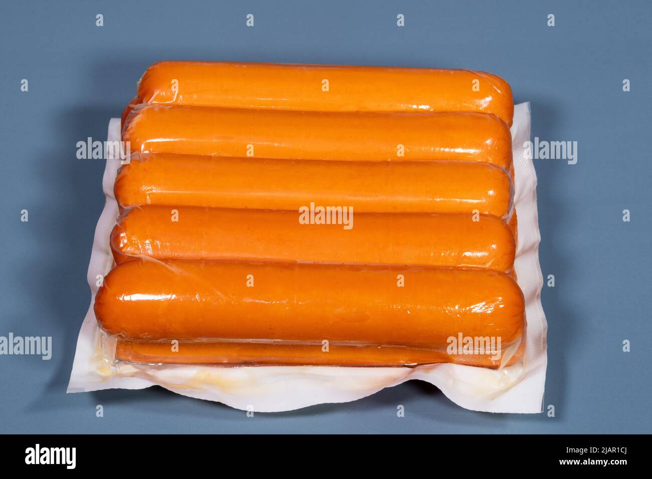 Sausage packaged in plastic by manufacturer on blue background, front