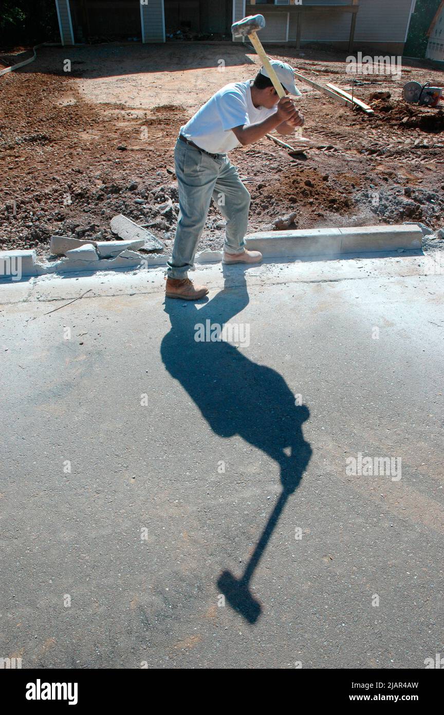 using Bobcat and hand sledge sledgehammers to level and clean dirt site of new home for cement