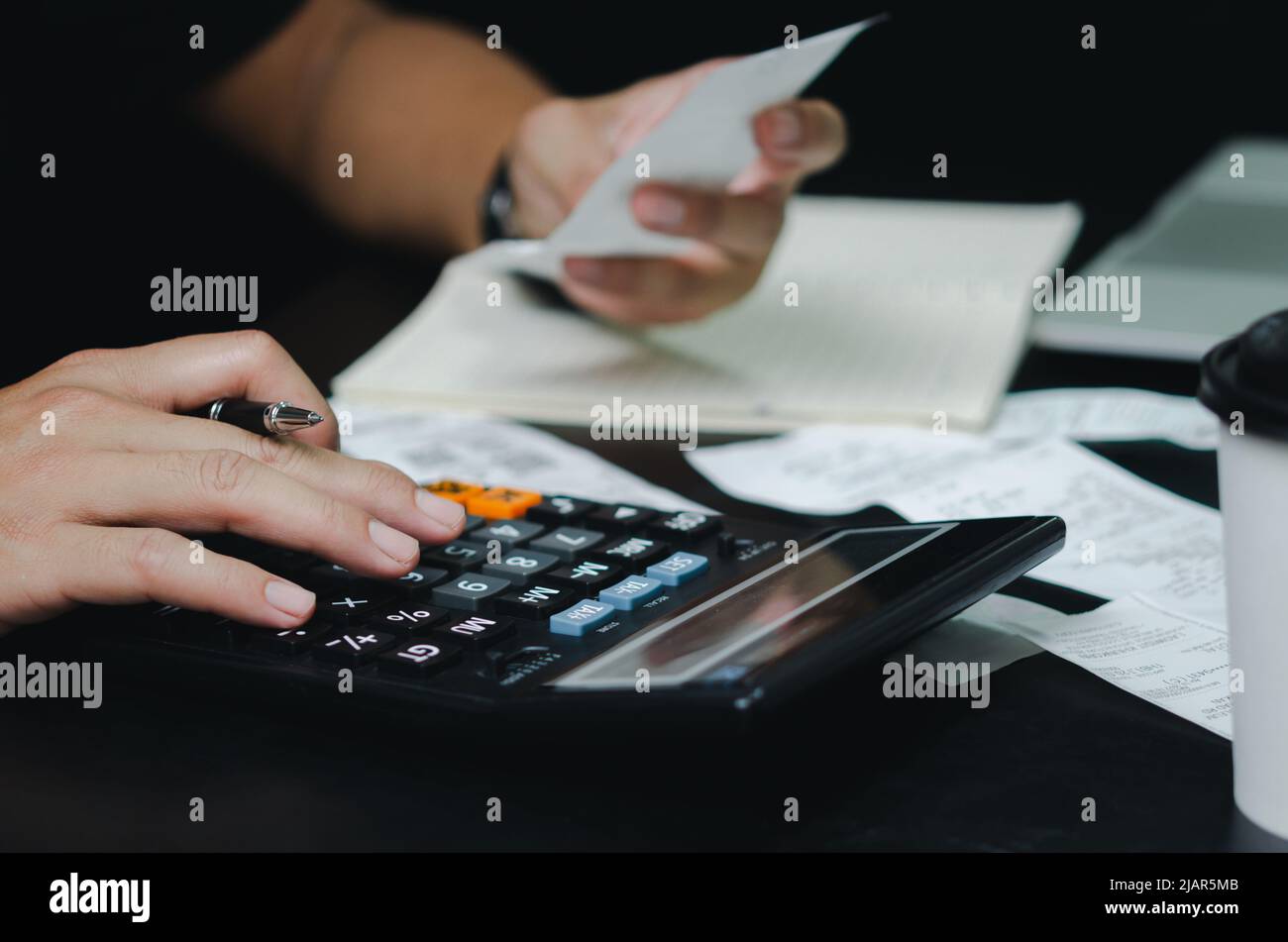 Man hand holding pen and calculator expense or tax receipt. business