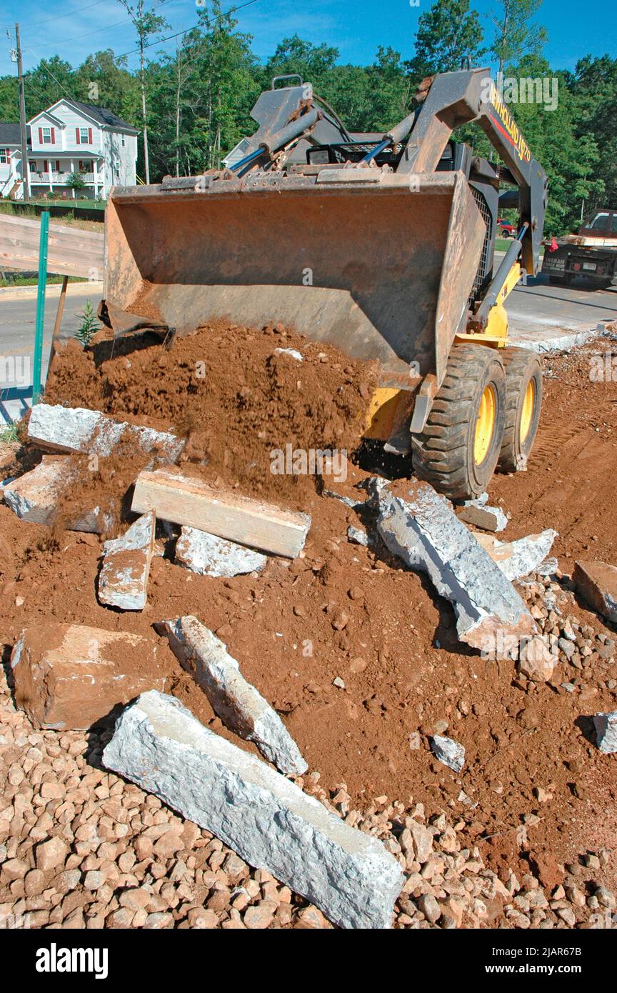 using Bobcat and sledgehammers to level and clean dirt site of new home