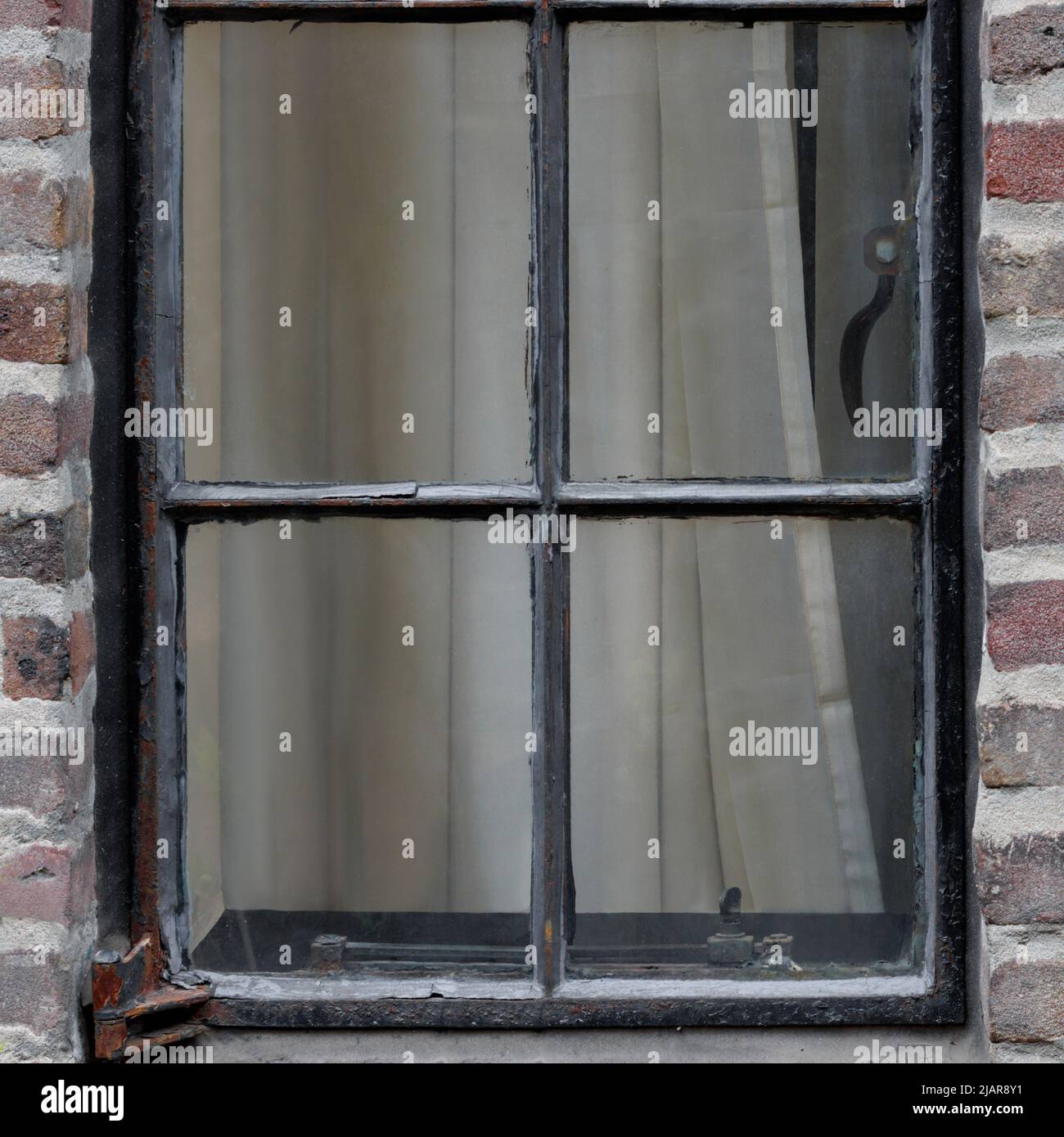 external view of antique casement window in an old red brick building, closed with curtains pulled, square format Stock Photo