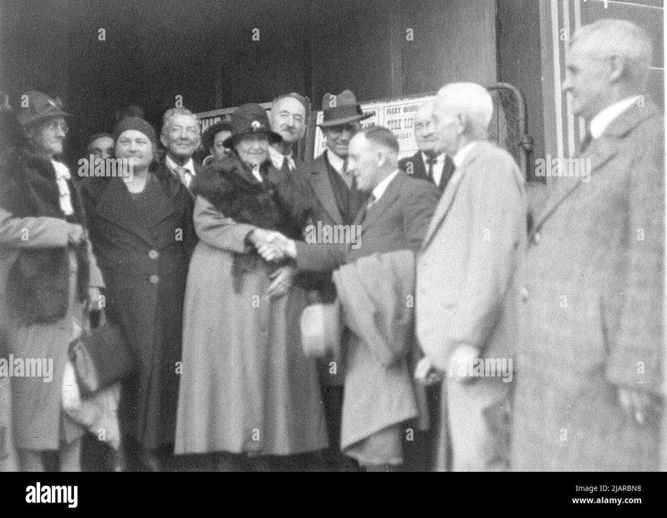 Jack (Jim) Beasley shaking hands with a lady. Crowd of other pensioners around at the Amusu Theatre (Darling Street, Balmain, New South Wales) ca.  31 August 1934 Stock Photo