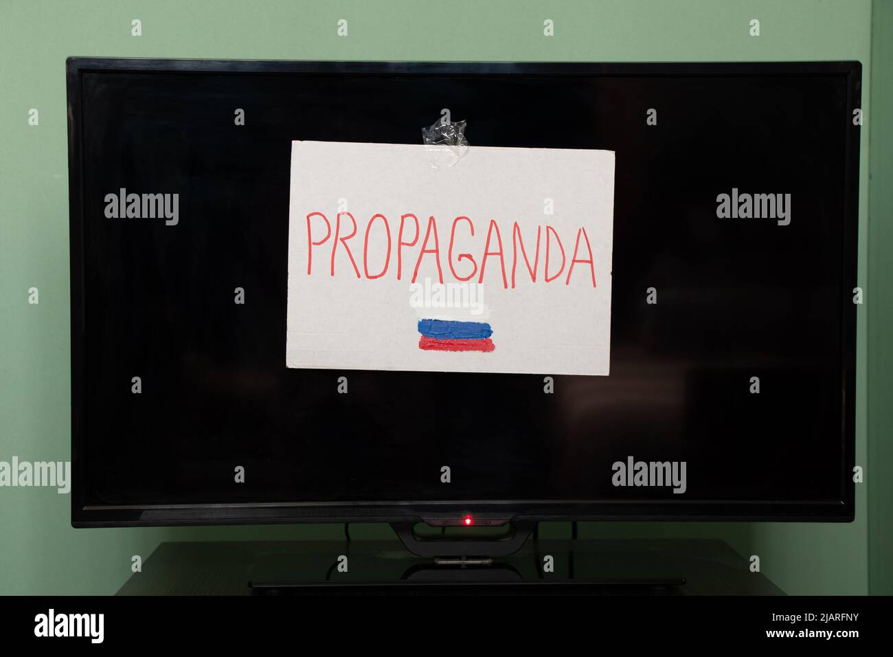 The word propaganda and the flag of Russia is written on a plate that hangs on the TV, Russian propaganda be careful, stop the war in Ukraine Stock Photo