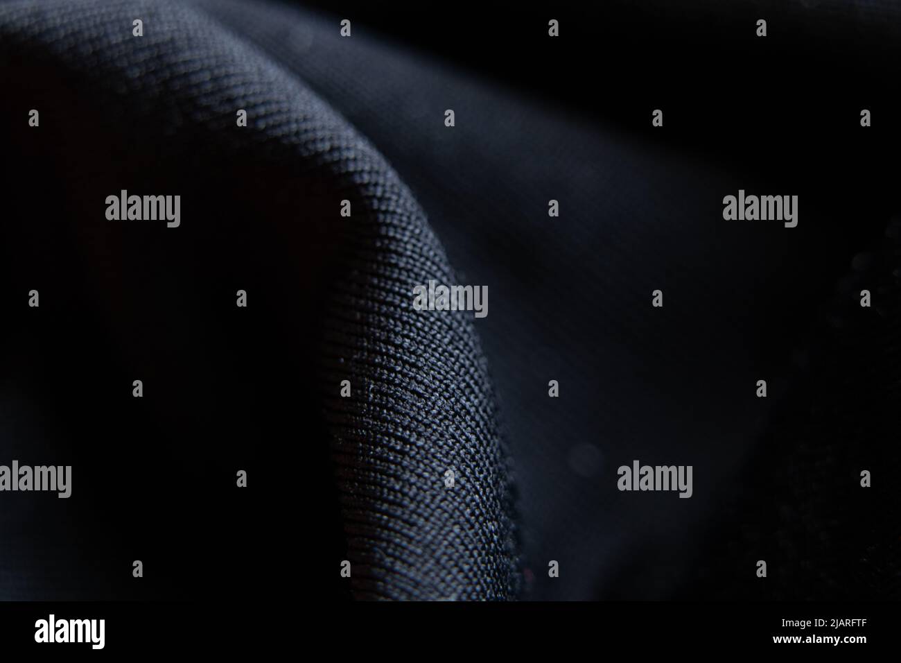 Black smooth fabric with a wave as a background, black background, fashion and texture Stock Photo