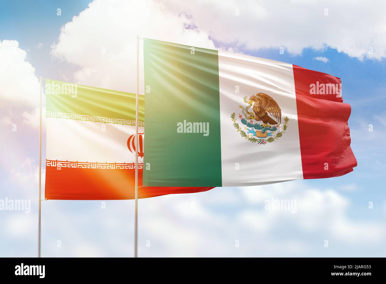 Sunny blue sky and flags of mexico and iran Stock Photo